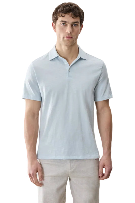 Man wearing a light blue polo shirt against a gray background