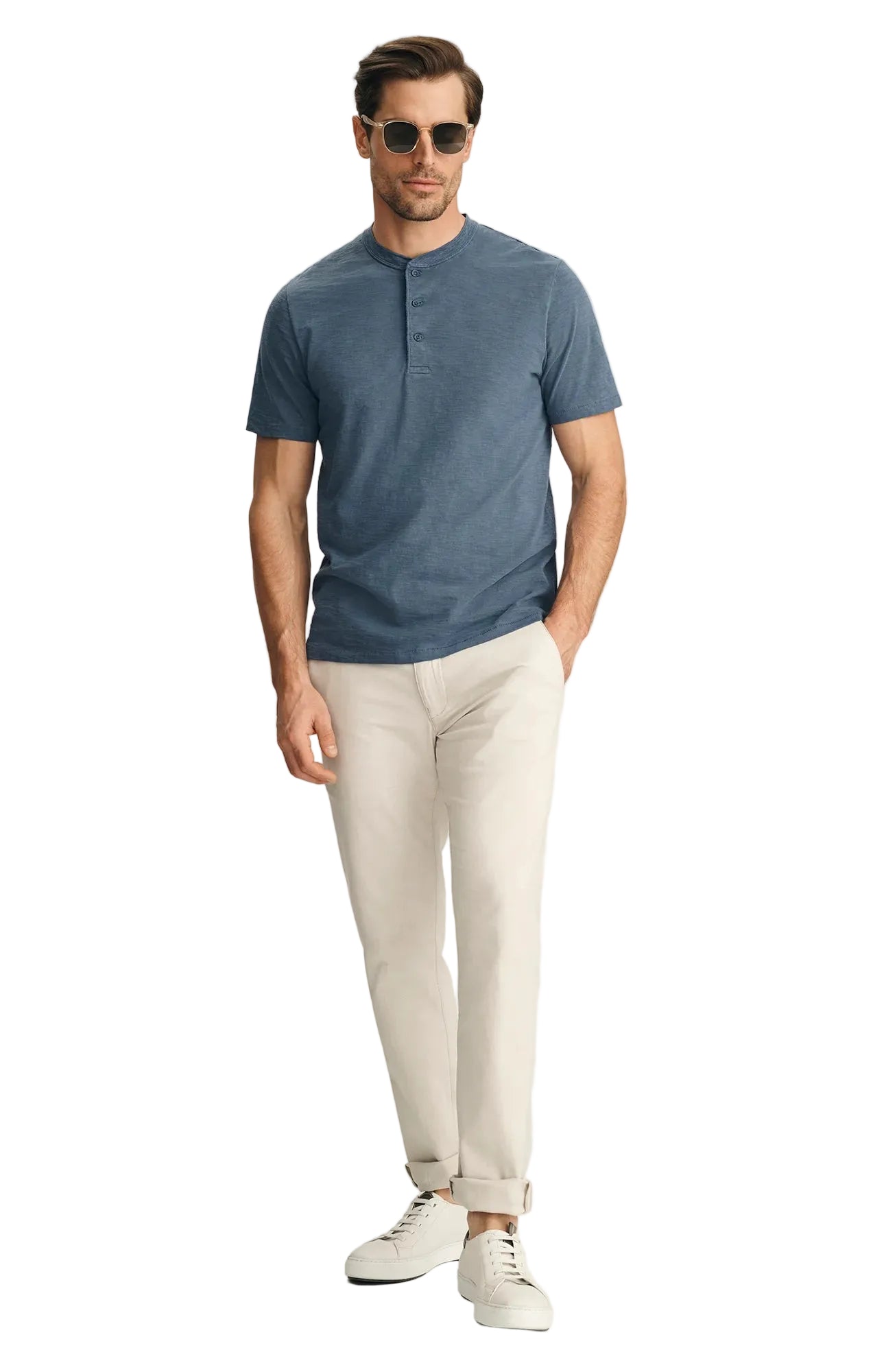 Man wearing a blue henley shirt, beige pants, and white sneakers on a light gray background