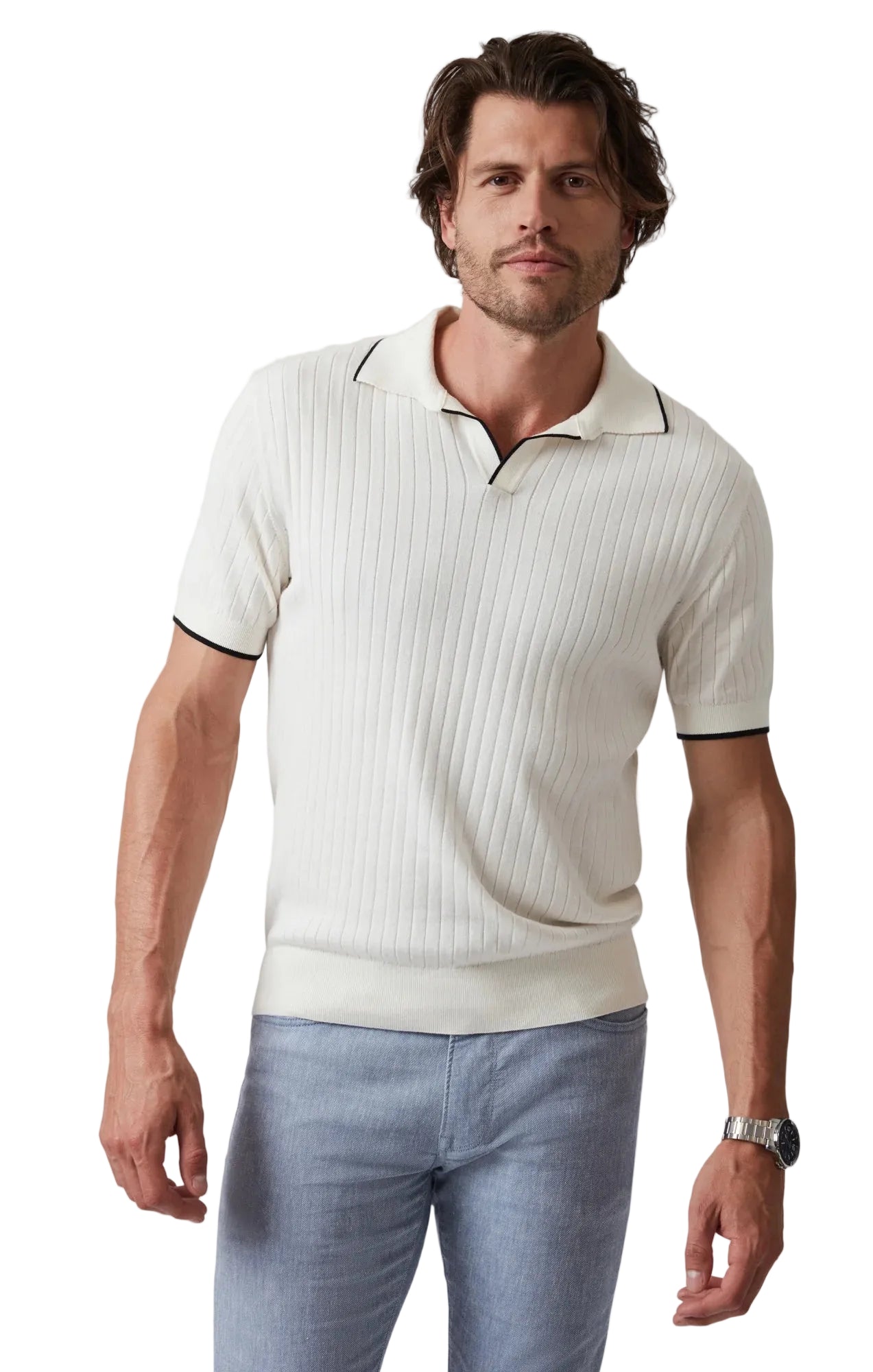 Man wearing a white ribbed polo shirt with black trim and light blue pants on a plain background
