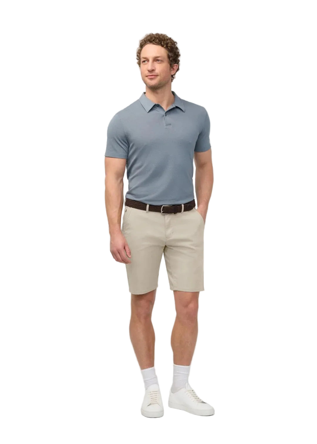Man wearing a light blue polo shirt, beige shorts, and white shoes on a plain background