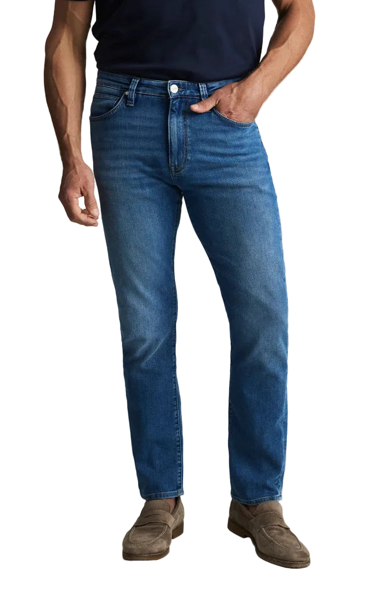 Person wearing blue jeans and brown shoes on a white background