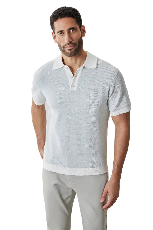 Man wearing a light gray polo shirt and beige pants against a plain background